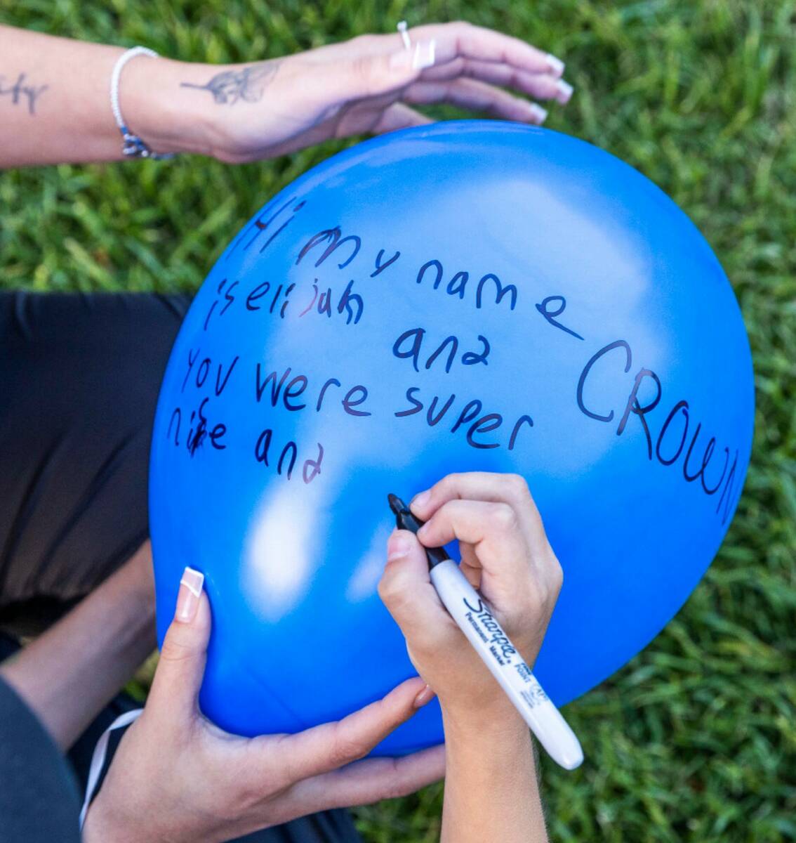 A young boy writes a message for Tabatha Tozzi, 26, her poems are inserted into balloons which ...