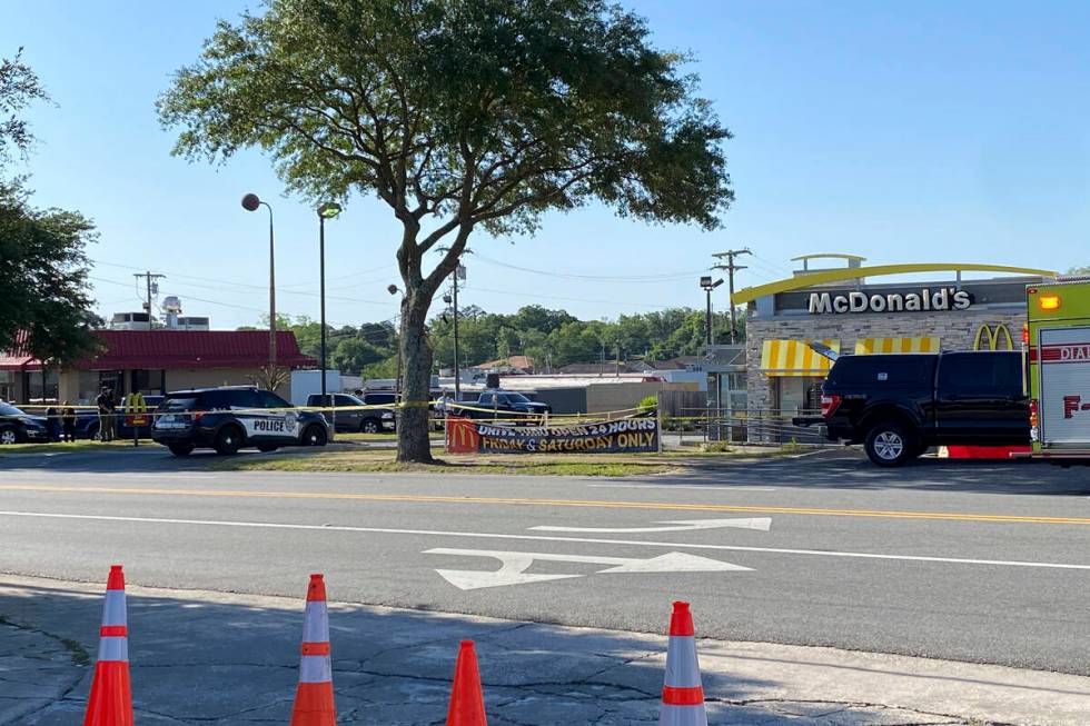 Police vehicles sit parked in front of a McDonald's restaurant as police investigate a shooting ...