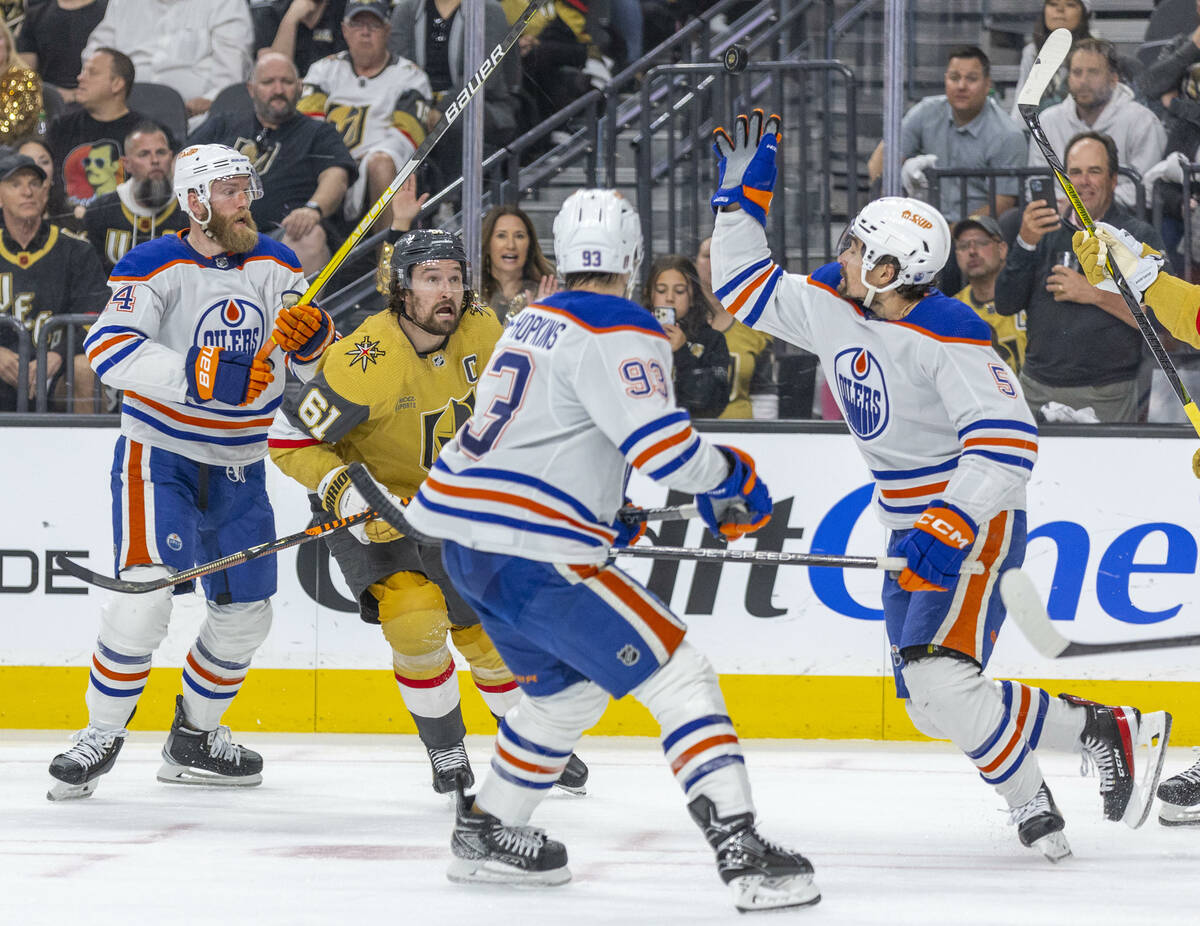 Edmonton Oilers defenseman Cody Ceci (5) looks to bats down a puck with teammate center Ryan Nu ...