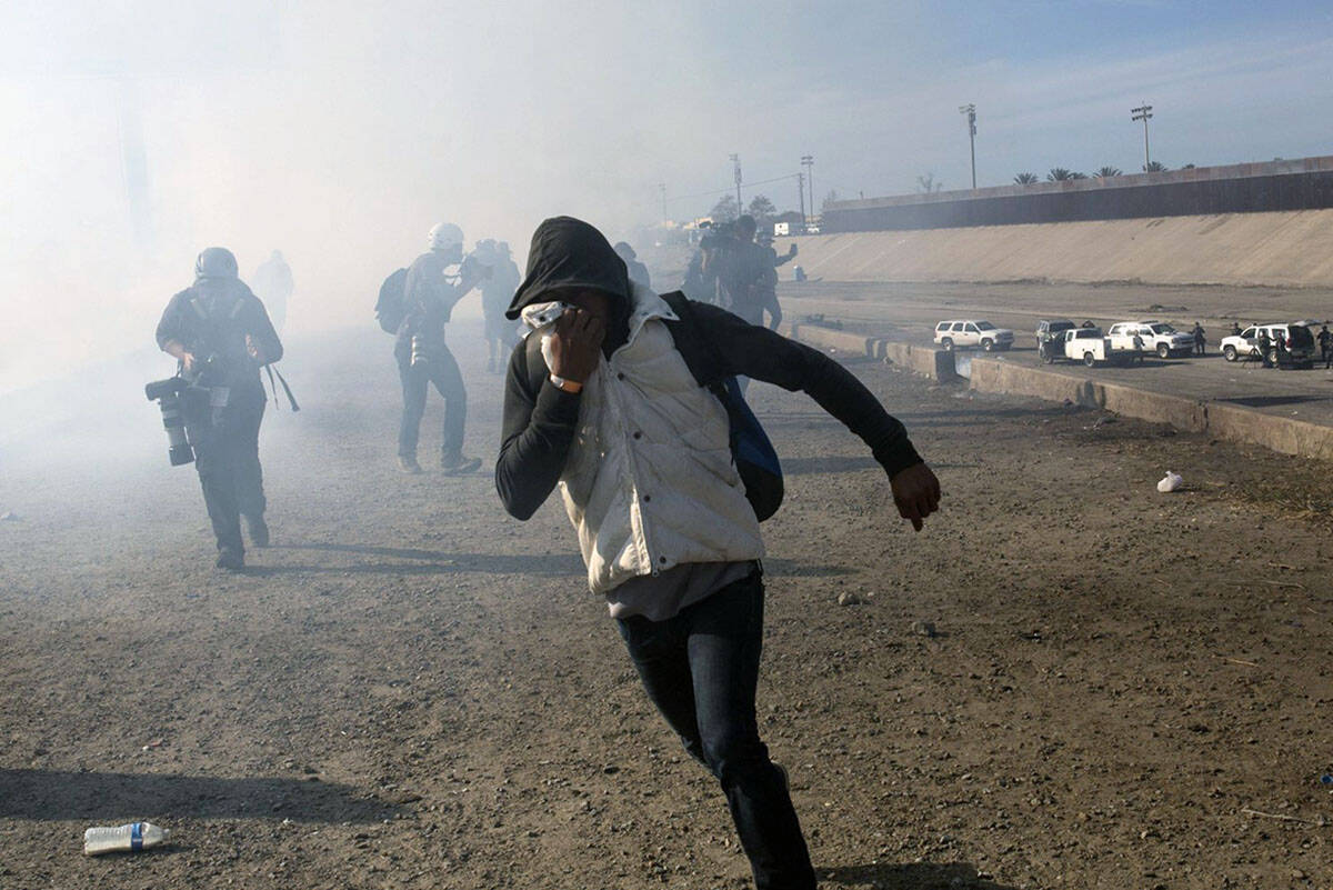 A migrant runs from tear gas launched by U.S. agents, amid members of the press covering the Me ...