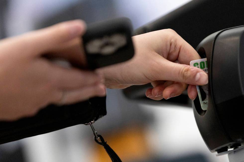 A traveler inserts her ID card while using the TSA's new facial recognition technology at a Bal ...