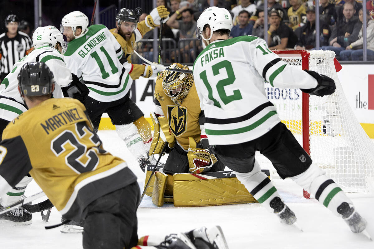 Golden Knights goaltender Adin Hill (33) saves the puck while defensemen Alec Martinez (23) and ...