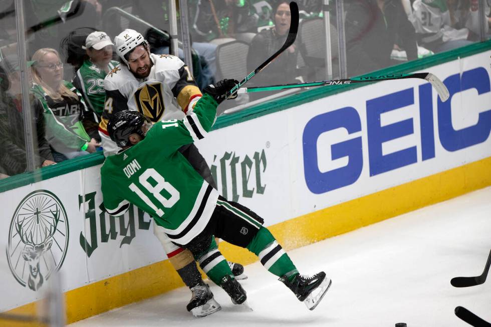 Golden Knights defenseman Nicolas Hague (14) takes a hit from Dallas Stars center Max Domi (18) ...