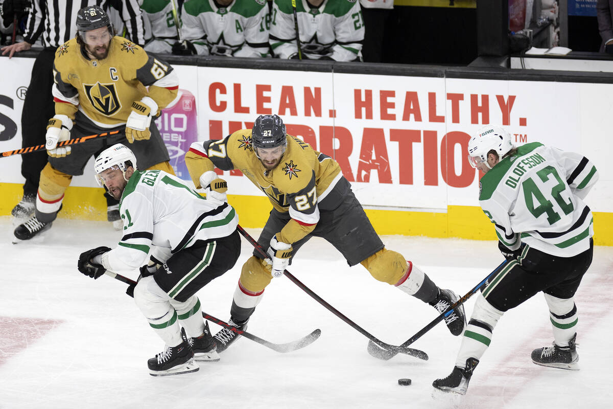 Golden Knights defenseman Shea Theodore (27) battles for the puck with Dallas Stars center Luke ...