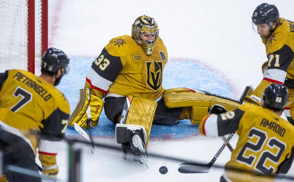 Golden Knights goaltender Adin Hill (33) looks to a loose puck with teammates during the first ...