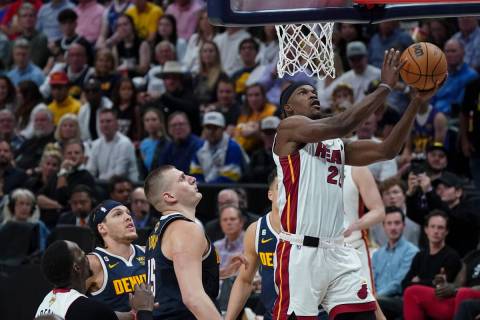Miami Heat forward Jimmy Butler (22) shoots the ball next to Denver Nuggets center Nikola Jokic ...