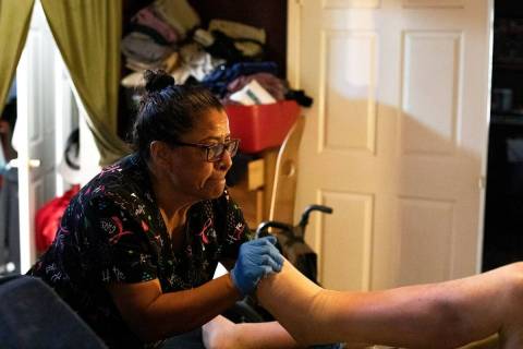 Personal care aid Irma Nunez stretches a client's legs in April 2021 in Las Vegas. (Ellen Schmi ...