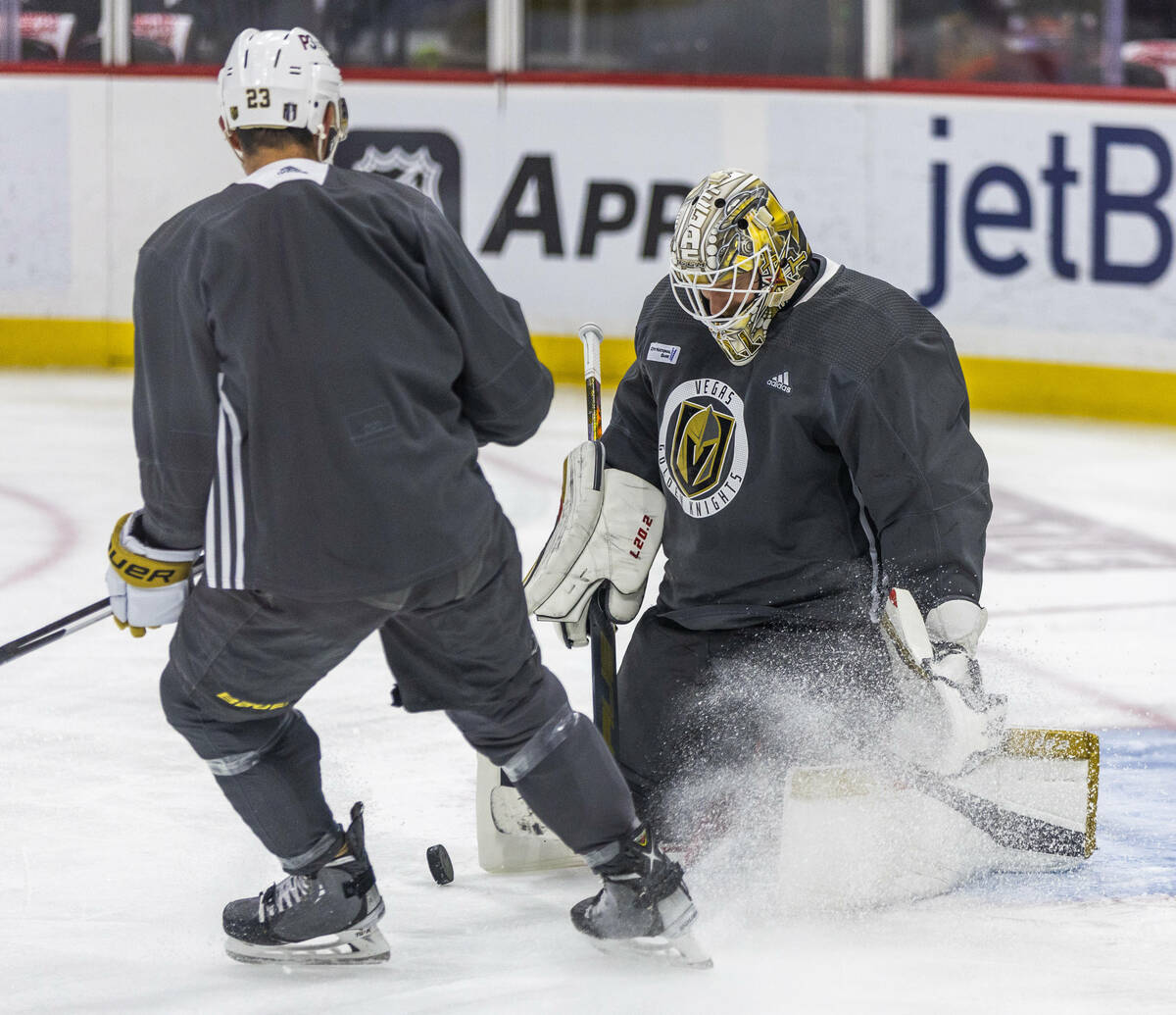 Golden Knights defenseman Alec Martinez (23) kicks up some ice while chasing a puck to goaltend ...