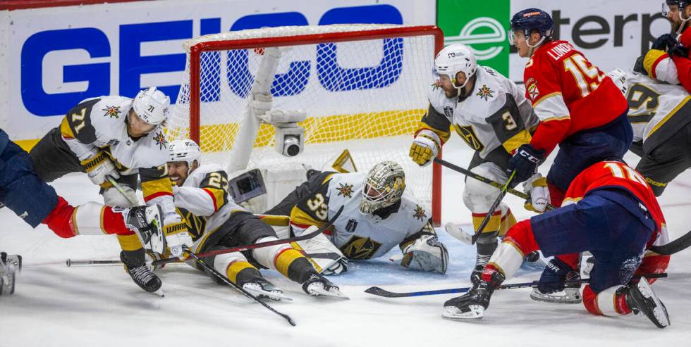 Golden Knights goaltender Adin Hill (33) and defenseman Shea Theodore (27) combine to save the ...