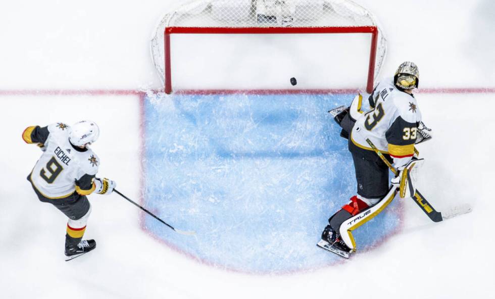 Golden Knights goaltender Adin Hill (33) and center Jack Eichel (9) watch the puck go in the ne ...