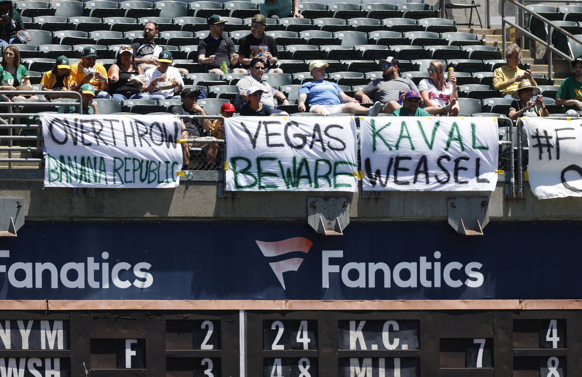 Baseball fans sit in front of homemade signs during the Texas Rangers game against the Oakland ...