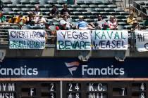 Baseball fans sit in front of homemade signs during the Texas Rangers game against the Oakland ...