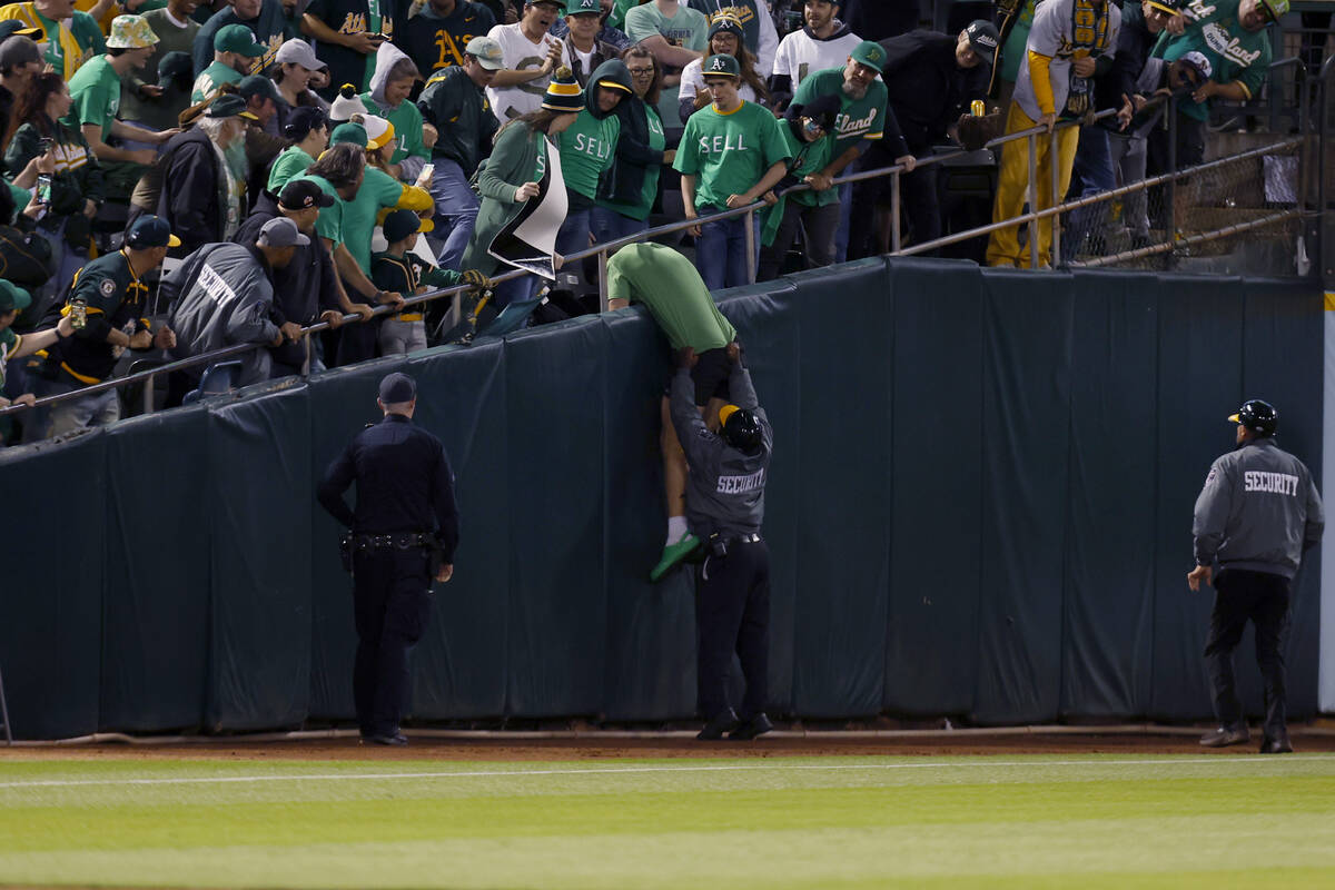 A security worker keeps a person who had run onto the field from climbing back into the stands ...