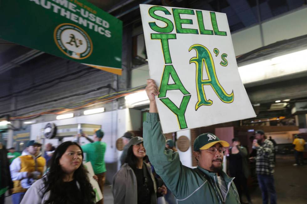 A fan holds a sign to protest the Oakland Athletics' planned move to Las Vegas, before a baseba ...