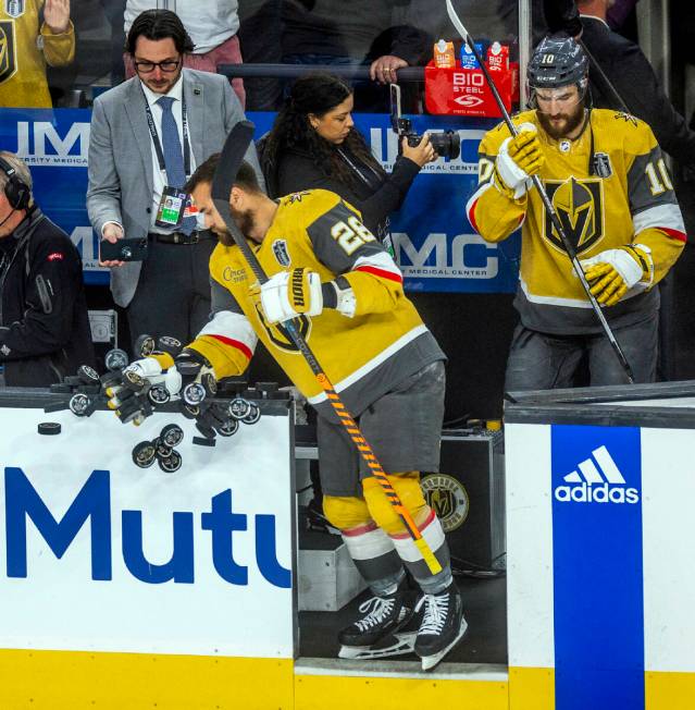 Golden Knights left wing William Carrier (28) knocks pucks off the bench rail for warmups befor ...