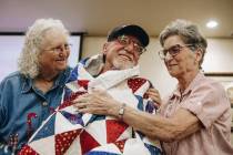 Doug Wilson, middle, is embraced by Quilts of Valor Foundation volunteers Gloria Britton, left, ...