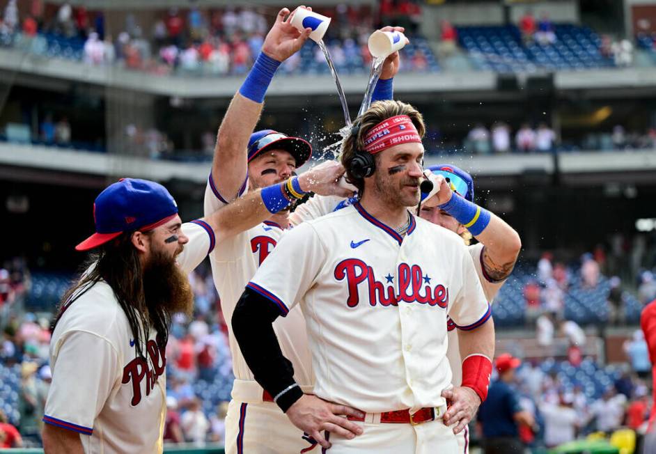 Philadelphia Phillies' Bryce Harper, center, is doused by teammates Brandon Marsh, left, Kody C ...