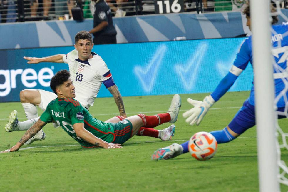 USA’s Christian Pulisic (10) scores a goal against Mexico goalie Guillermo Ochoa (13) as ...