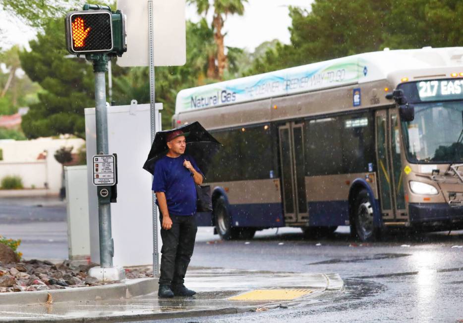 A man waits to cross Pecos road during an early morning rain storm on Friday, June 16, 2023, in ...