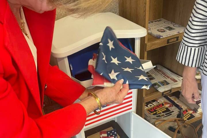 Jan Butler removes flags from the new flag disposal bin at the Paseo Verde Library on May 30. ( ...