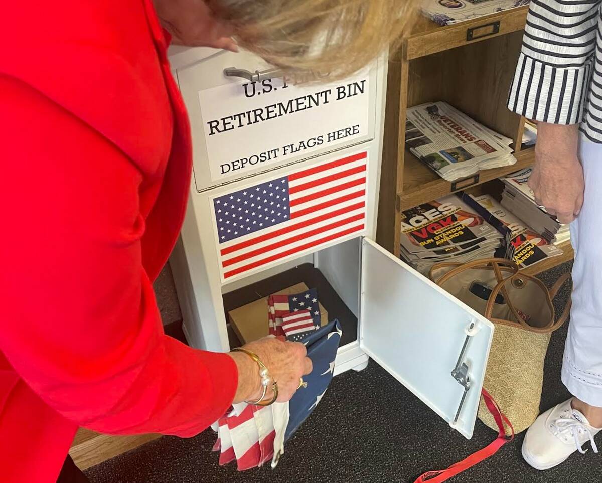 Jan Butler removes flags from the new flag disposal bin at the Paseo Verde Library on May 30. ( ...