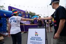 A Los Angeles Dodgers Pride promoter gives a ball to a participant at the WeHo Pride Parade in ...