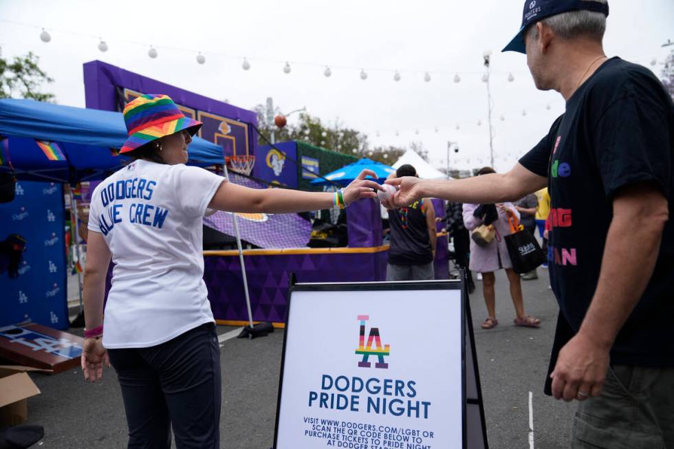 A Los Angeles Dodgers Pride promoter gives a ball to a participant at the WeHo Pride Parade in ...