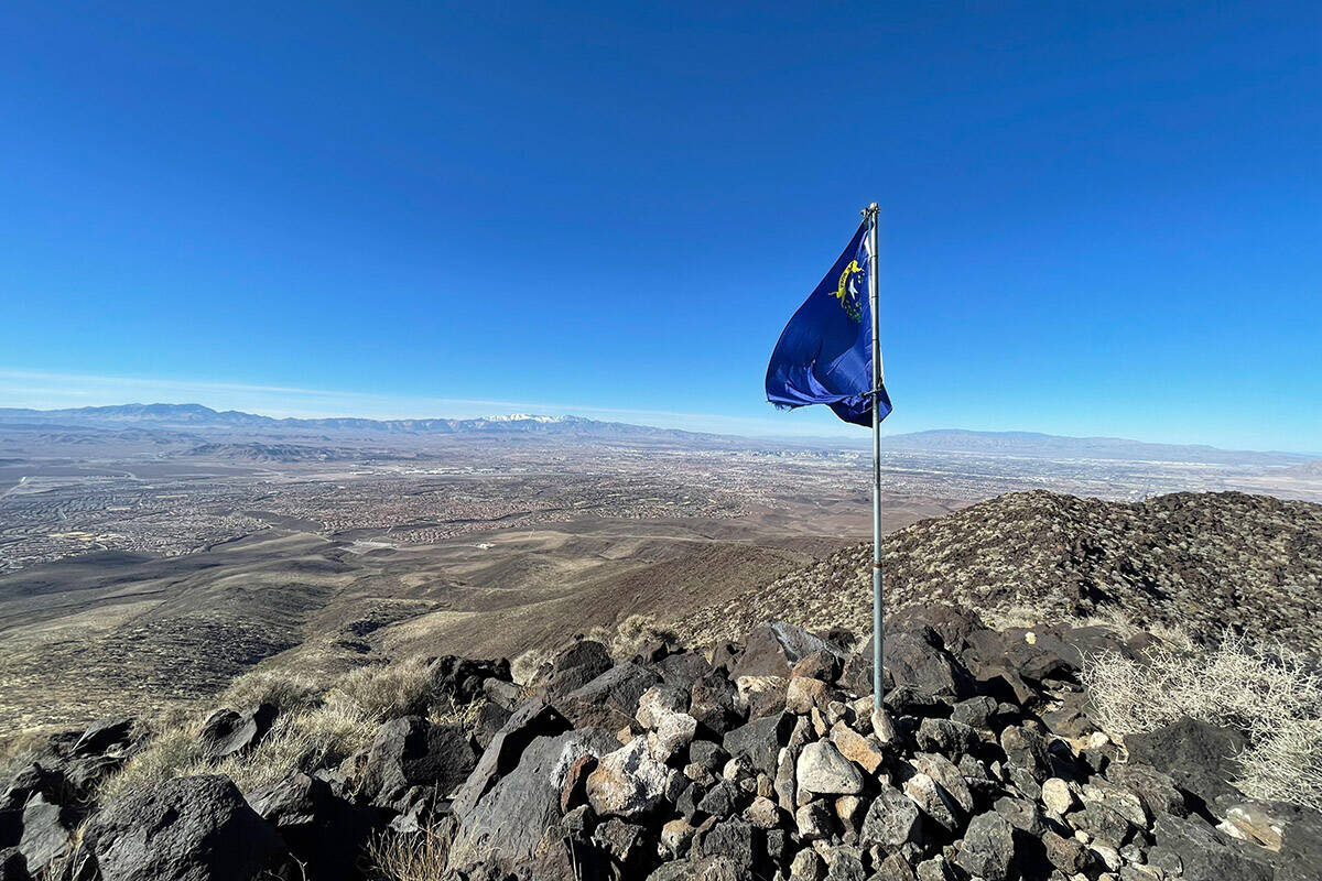 A Nevada flag blows in the wind at the peak of Black Mountain in Sloan Canyon National Conserva ...