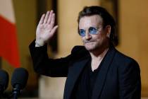 Bono waves good-bye to the media after a meeting with French President Emmanuel Macron at the E ...