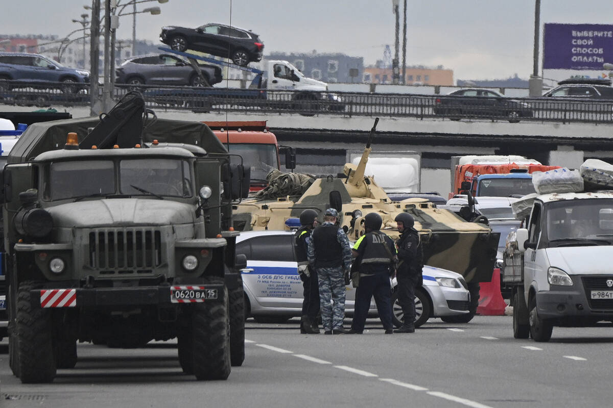 An APC and police officers stand on the highway on the outskirts of Moscow, Russia, Saturday, J ...