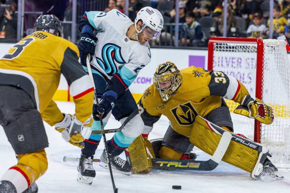 Golden Knights goaltender Adin Hill (33) defends the net from Seattle Kraken center Alex Wennbe ...