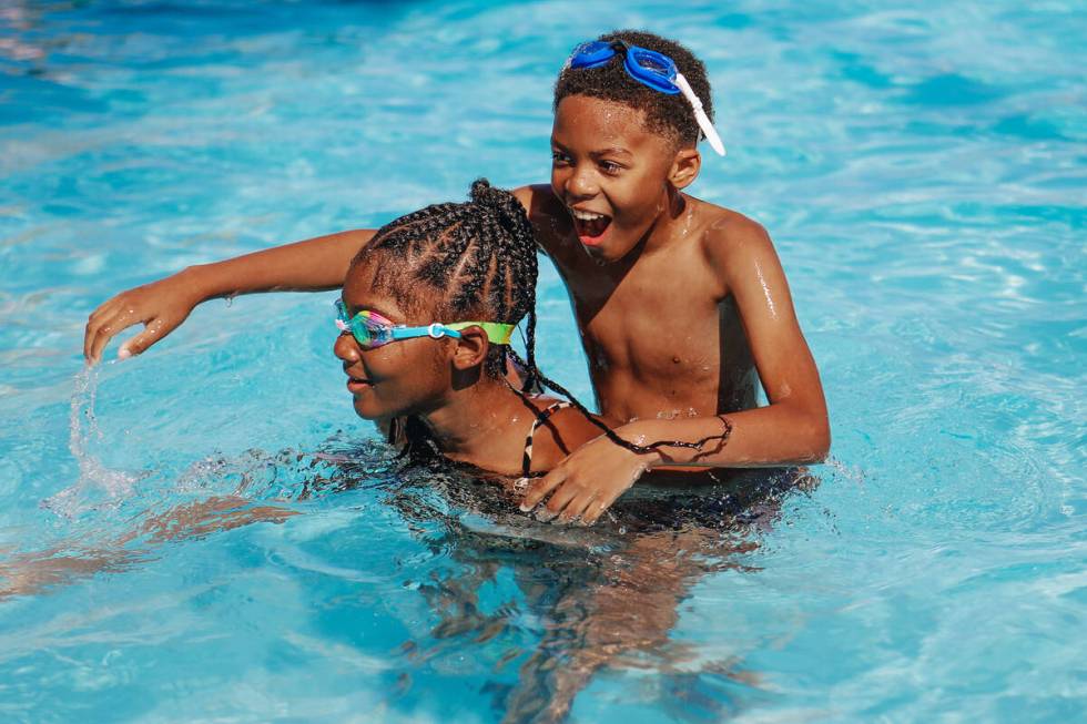 Terell Durham, 9, right, gets a piggyback ride from Daziya Smothers, 9, as they play in the poo ...