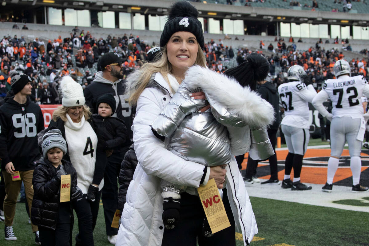 Derek Carr’s wife, Heather, holds their daughter, Brooklyn, as she is followed off the f ...