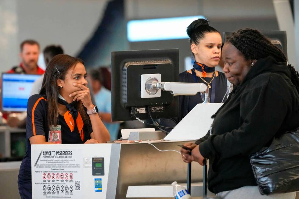 Jet Blue agents help a traveler, right, in the departures area of Terminal B at LaGuardia Airpo ...