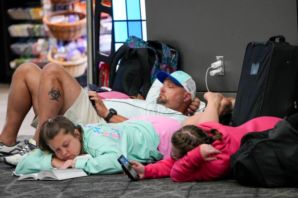 Travelers use their electronic devices while lying on the floor of the departures area of Termi ...
