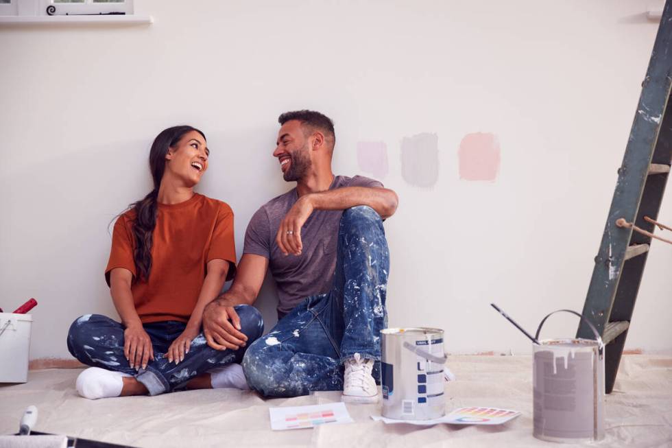 A couple take a break from painting test squares on the wall. Choosing the wrong color is often ...