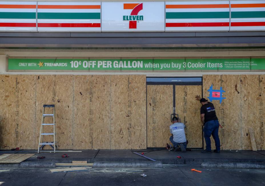 Workers board up the 7-Eleven on Boulder Highway and South Lamb Boulevard where a person was ki ...