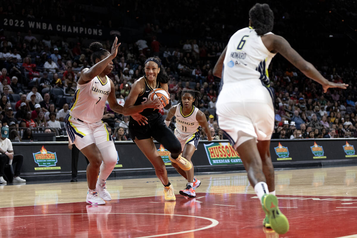 Las Vegas Aces forward A'ja Wilson (22) drives toward the hoop between Dallas Wings center Teai ...