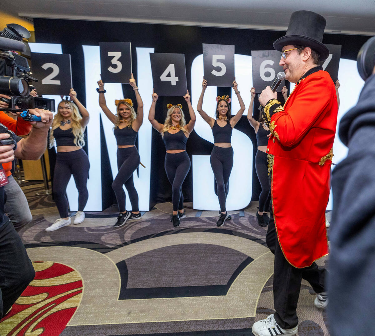 Models enter and hold numbers representing Phil Hellmuth's 17 gold bracelets as the “The ...