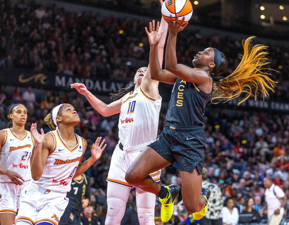 Aces guard Jackie Young (0) elevates around Phoenix Mercury center Megan Gustafson (10) for ano ...