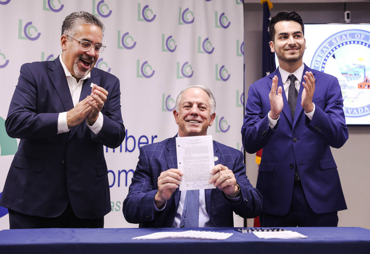 Peter Guzman, president of the Latin Chamber of Commerce, from left, looks on as Gov. Joe Lomba ...