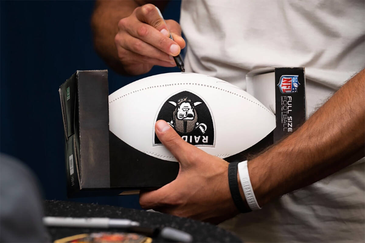 Jimmy Garoppolo, Las Vegas Raiders quarterback, signs a football during a meet and greet at Nel ...