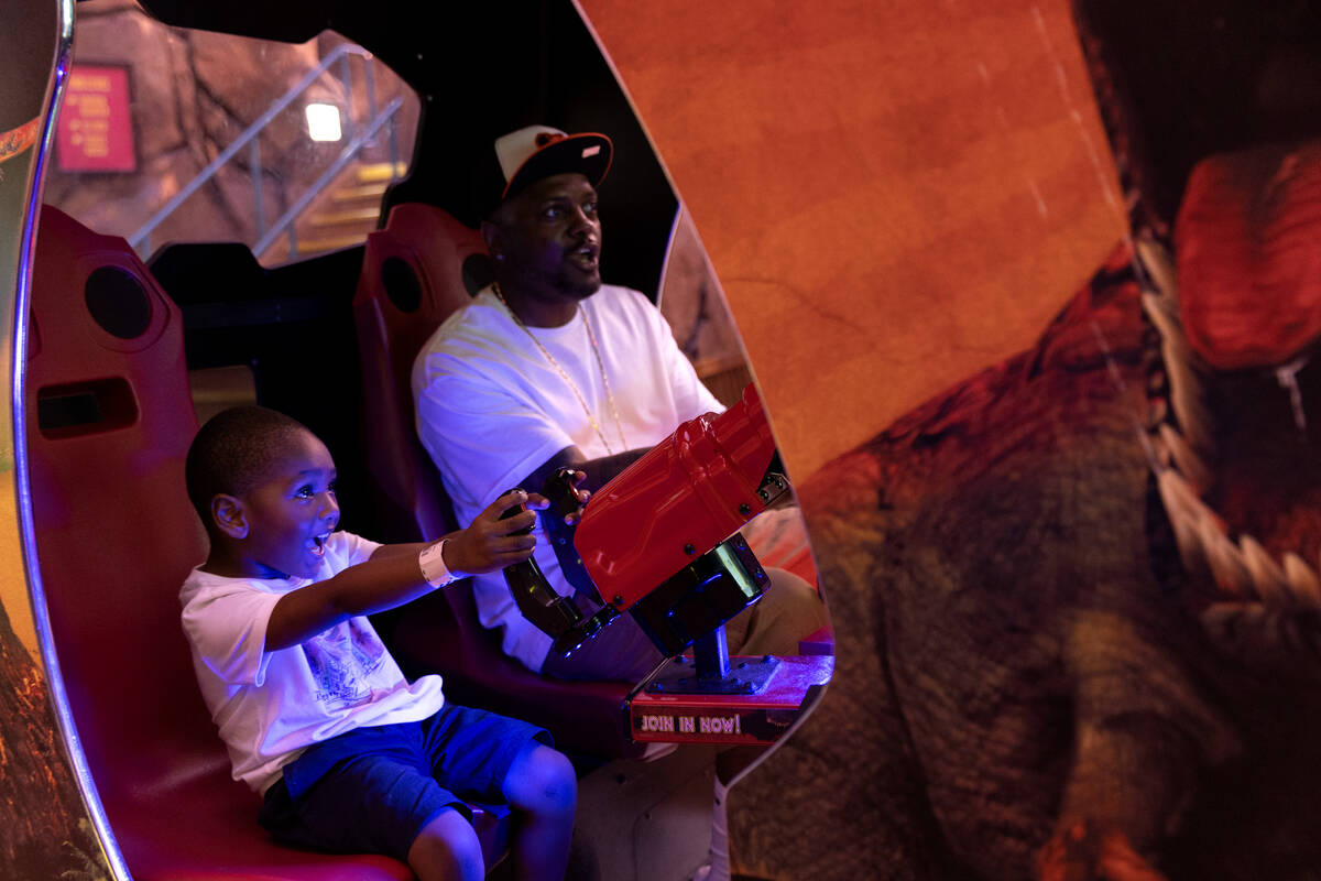 Baby Ernie Davis, 4, and his grandfather DeShawn Allen, of Seattle, play a Jurassic Park arcade ...