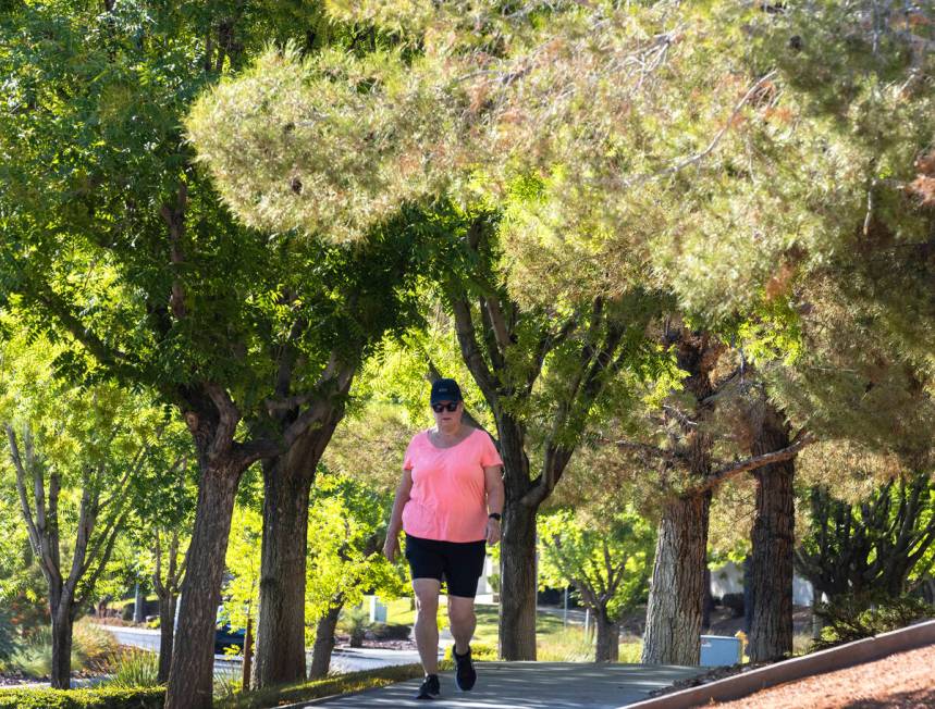 A pedestrian walks on a tree-covered sidewalk along Green Valley Parkway on Thursday, July 20, ...