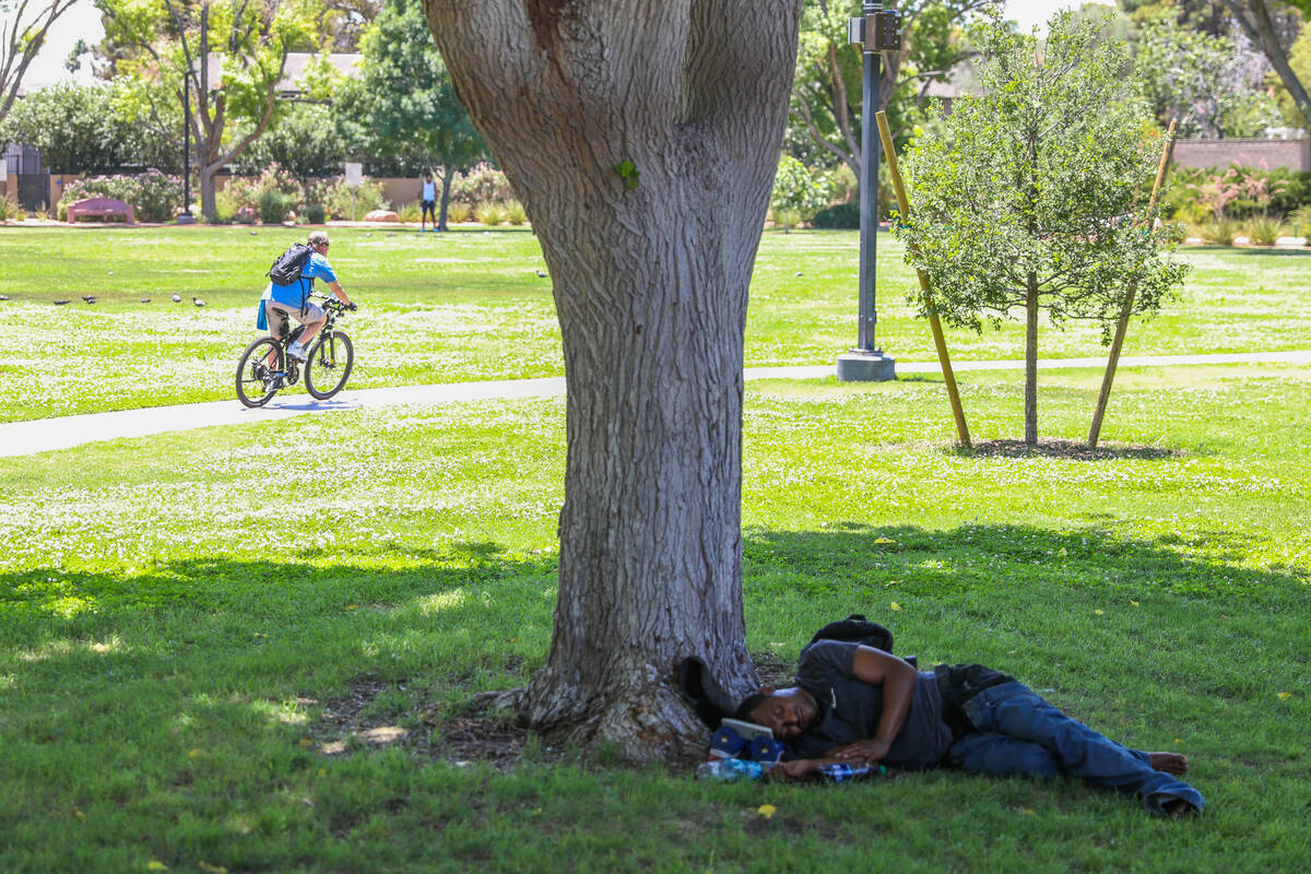 A man rests in the shade underneath a tree at Bob Baskin Park to cool down during the 110-degre ...