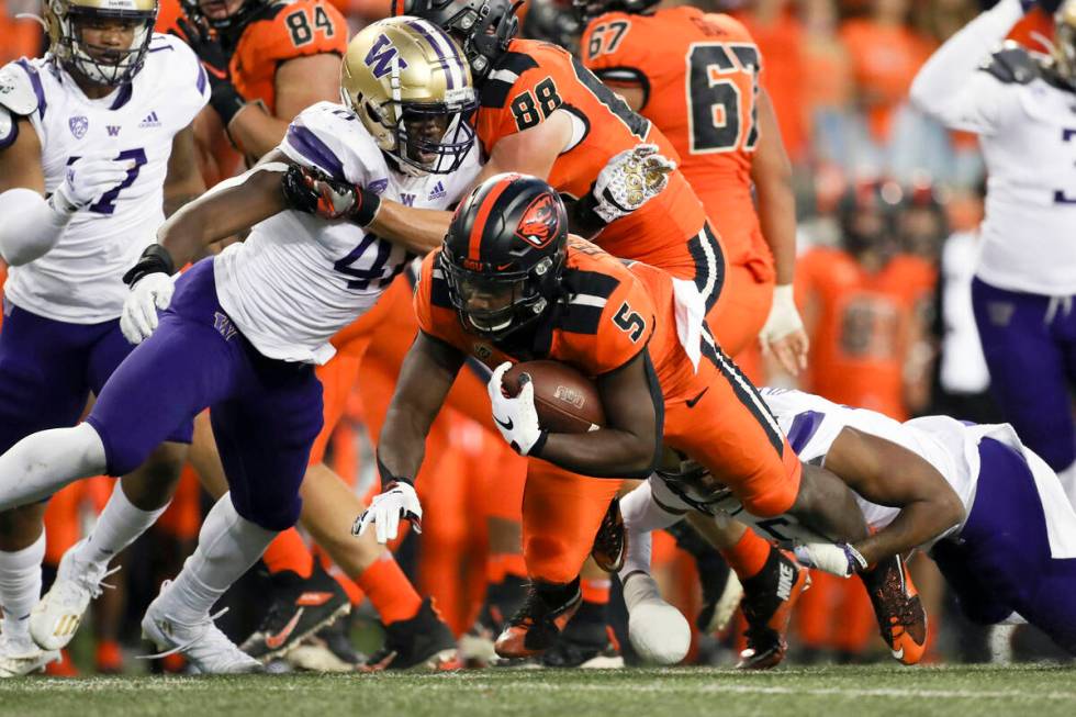 Oregon State running back Deshaun Fenwick (5) is brought down by Washington's Edefuan Ulofoshio ...