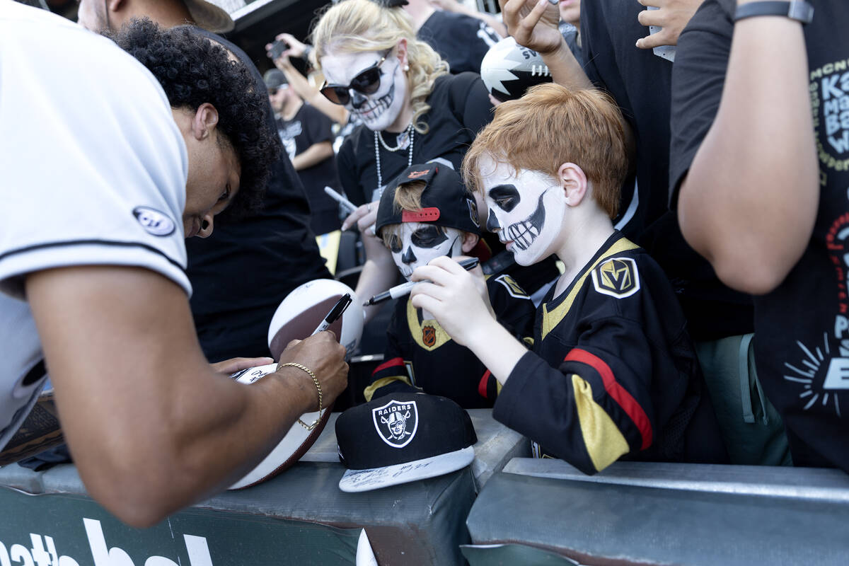 Twins Alex Kheel, center, and Ezra Kheel, right, both 7, have footballs signed by Raiders safet ...