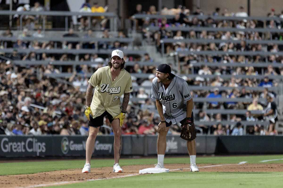 Golden Knights goaltender Logan Thompson and Raiders punter A.J. Cole III laugh at third base d ...