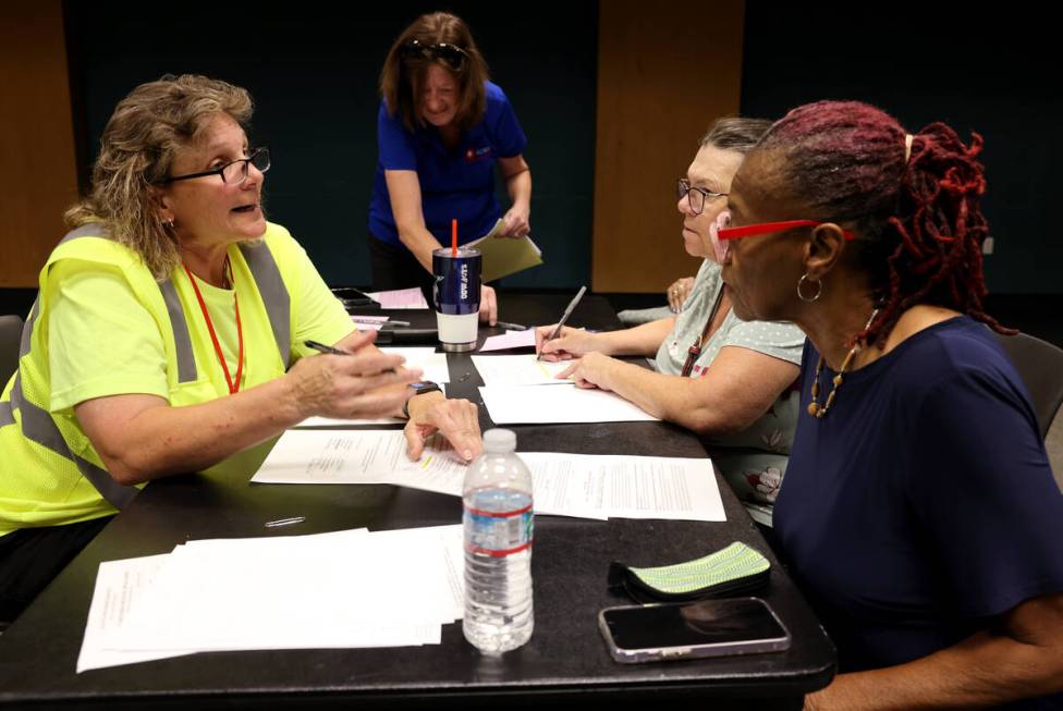 Connie Ames with All City Management Services, left, helps Ann Rhodes during a school crossing ...