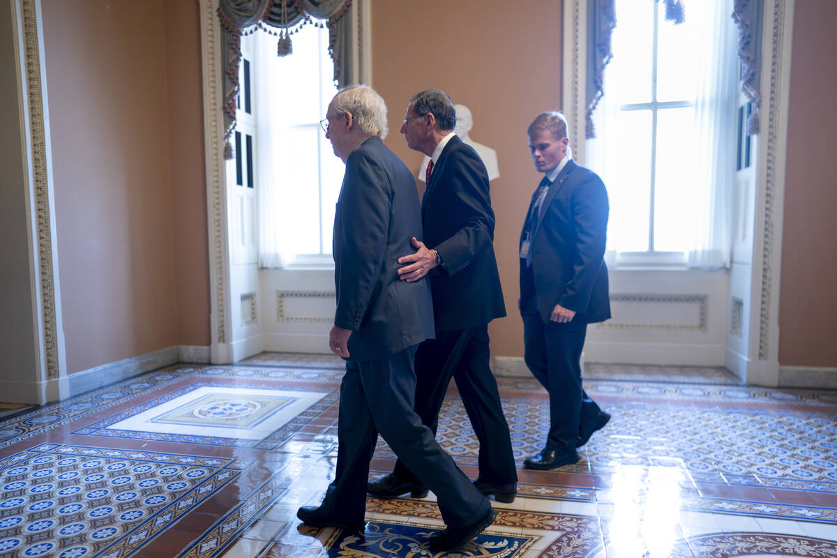 Senate Minority Leader Mitch McConnell, R-Ky., left, is assisted by Sen. John Barrasso, R-Wyo., ...